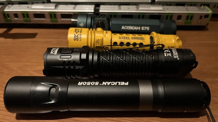A SK-07 amarela da Loop Gear em comparação com a Acebeam E75 (atrás), a Nitecore P27i e a Pelican 5050R