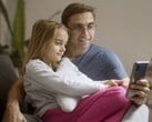 Um pai e sua filha olhando juntos para um smartphone