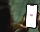 Mulher segurando um smartphone com as duas mãos; a tela exibe a página inicial do Instagram