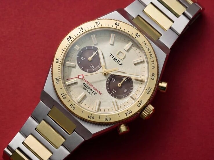 Close-up do relógio Timex Q Timex Continental Chronograph TW2Y92300 usado no pulso, mostrando seu mostrador dourado, submostradores marrons, luneta taquimétrica e pulseira de aço inoxidável bicolor.
