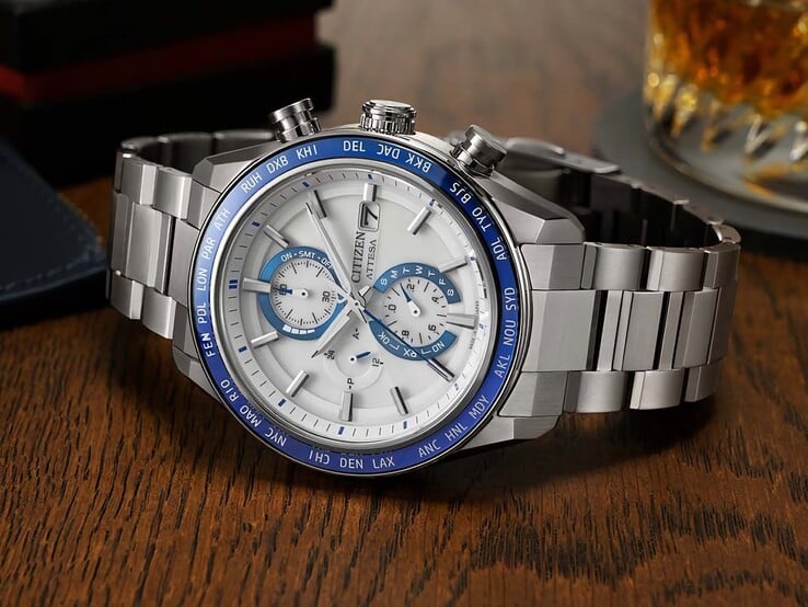 Cronógrafo Citizen Attesa AT8297-51L apoiado sobre uma mesa de madeira, mostrando seu mostrador azul-marinho, detalhes em ouro rosé e luneta preta com indicação de horário mundial.