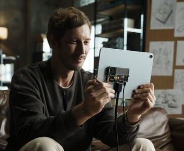 Usuário conectando o SSD portátil transparente Sharge Disk Pro com resfriamento ativo a um tablet via cabo USB-C. (Sharge via Kickstarter)