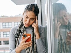 Uma mulher olha para o smartphone com uma expressão séria