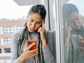 Uma mulher olha para o smartphone com uma expressão séria