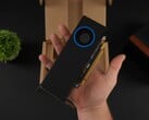 Uma pessoa segurando a GPU para estação de trabalho de baixo perfil Intel Arc Pro B50 com um cooler do tipo soprador, mostrada contra a caixa da embalagem. (Fonte da imagem: ETA Prime via YouTube)