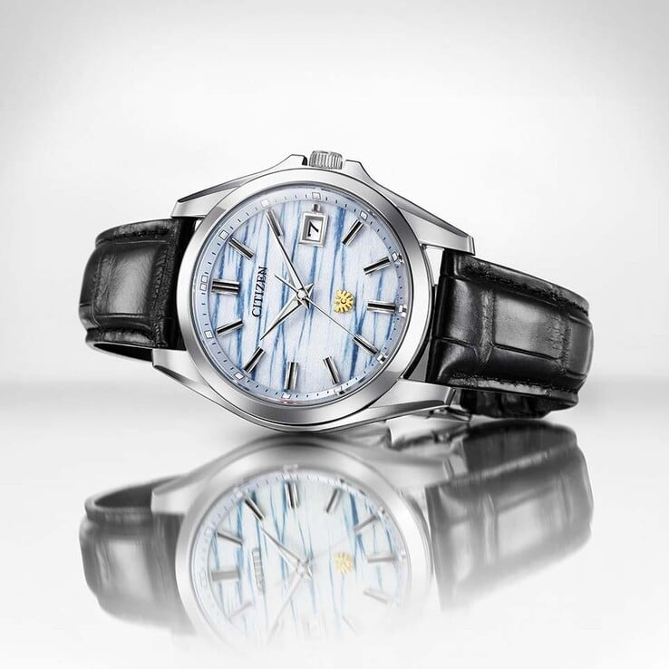 O relógio Citizen AQ4090-08A repousa sobre uma superfície reflexiva, destacando seu mostrador em papel washi índigo e sua pulseira de couro preta.